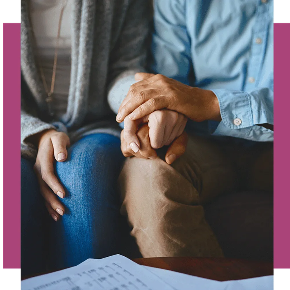 Elderly person holding a young womans hand to comfort her