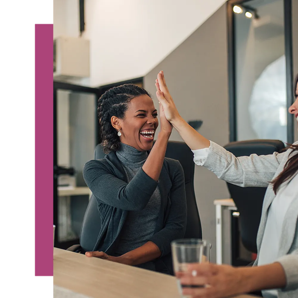 Two women laughing, high fiving each other