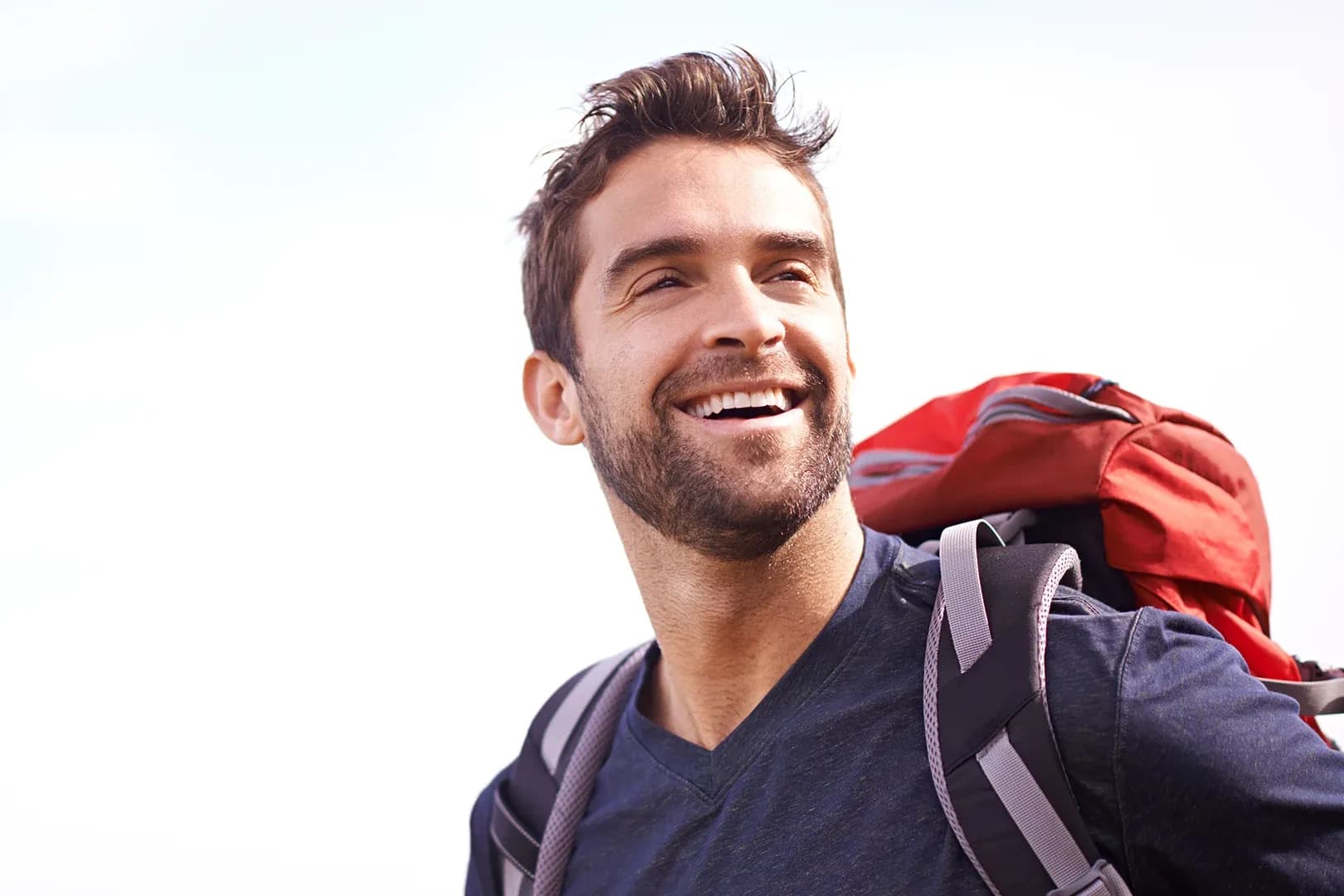 male hiker looking up into the distance wearing a backpack