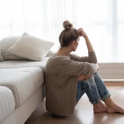 A women sat on the floor resting her head against her knuckle