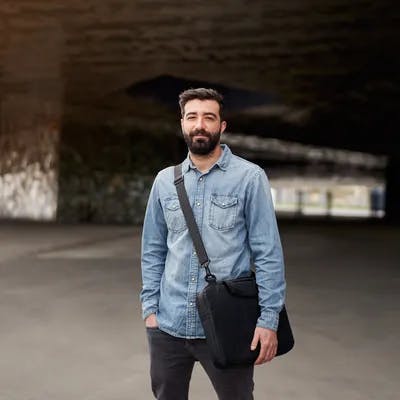 Young man stood in front of a tunnel with a bag